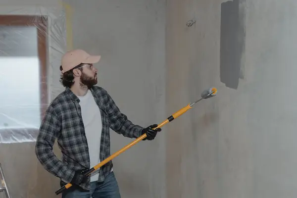 Painter rolling grey paint onto an interior wall in Peoria